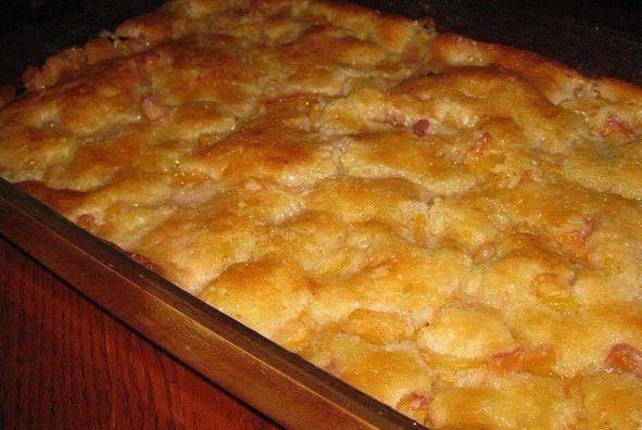 A baking dish filled with "Lazy Man's" Peach Cobbler and a scoop of vanilla ice cream on top.