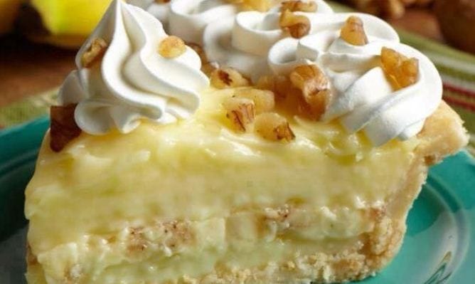 A slice of Old Fashioned Banana Cream Pie topped with whipped cream and banana slices.