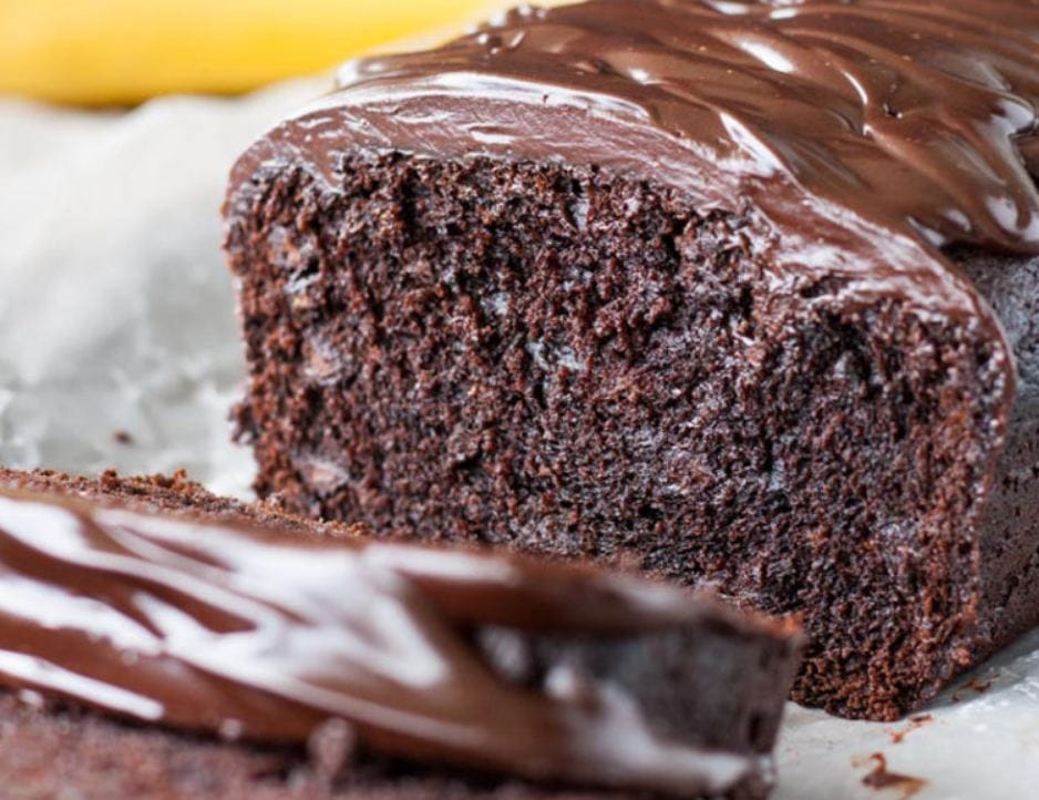 A loaf of triple chocolate banana bread on a cutting board with slices.