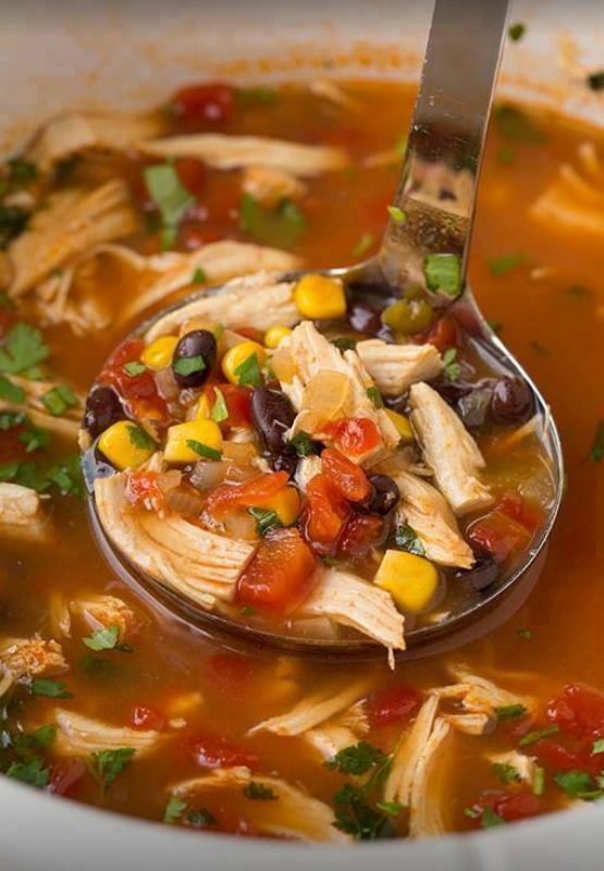 Crock Pot filled with chicken, vegetables, and broth for Chicken Tortilla Soup.