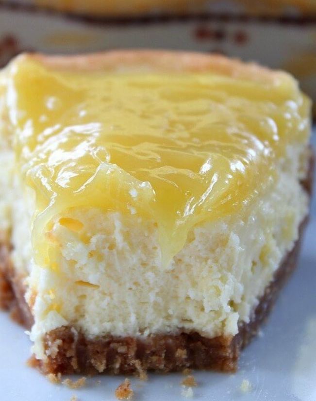 A photo of a slice of luscious lemon cheesecake on a plate, with a lemon slice and a mint sprig as garnish.