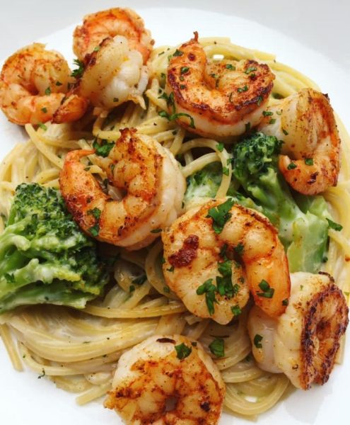 A plate of Shrimp and Broccoli Alfredo pasta, topped with fresh shrimp and broccoli
