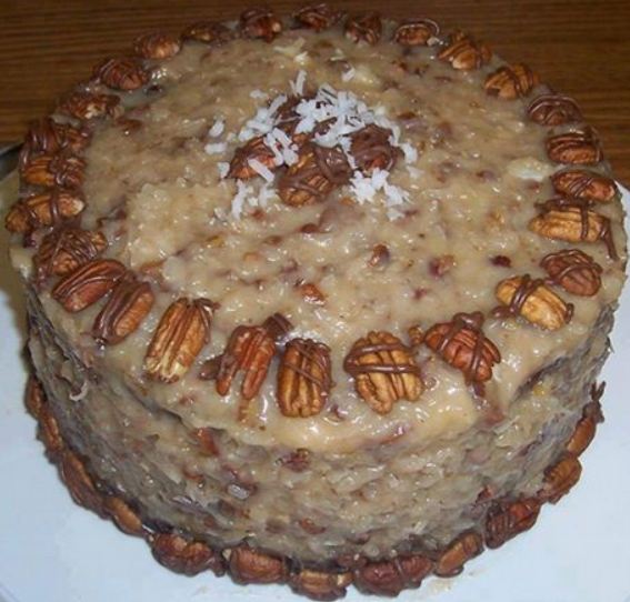 German chocolate cake with layers of chocolate cake, coconut pecan filling and chocolate ganache topping on a cake platter