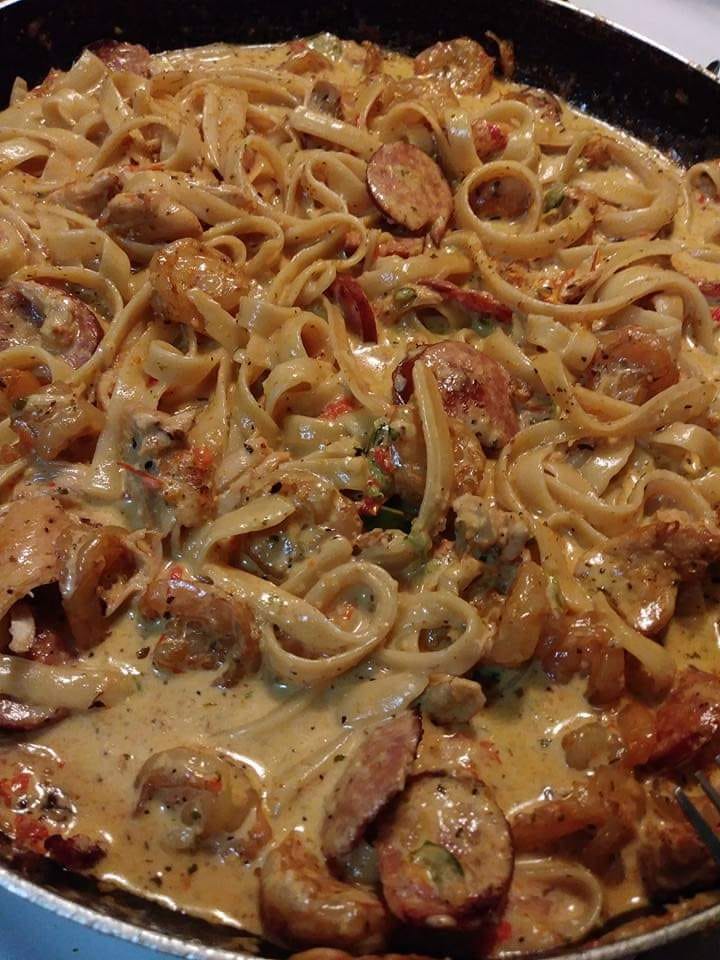 A plate of Cajun pasta with shrimp and sausage, garnished with parsley