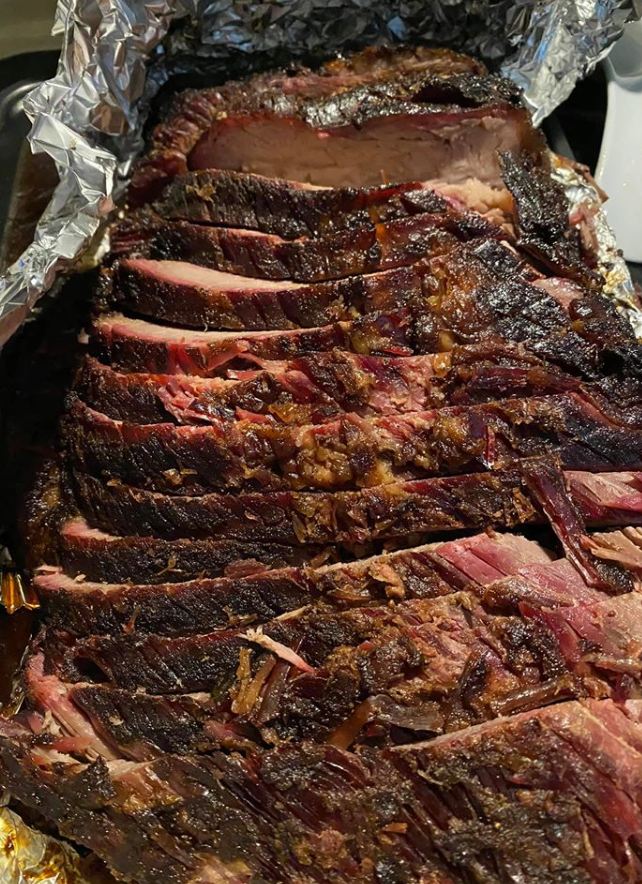 Smoked brisket with BBQ sauce on a wooden cutting board