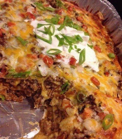 Walking Taco Casserole – Layers of seasoned beef, beans, and cheese in a 9x13 inch baking dish, ready for a delicious bake.