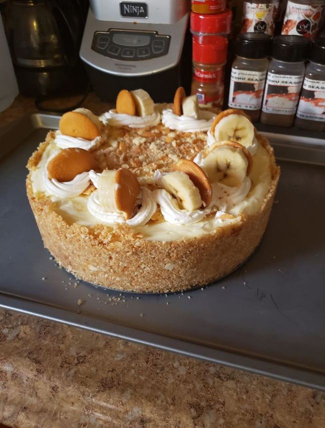 A mouthwatering slice of Banana Pudding Cheesecake on a plate, garnished with whipped cream and a banana slice.