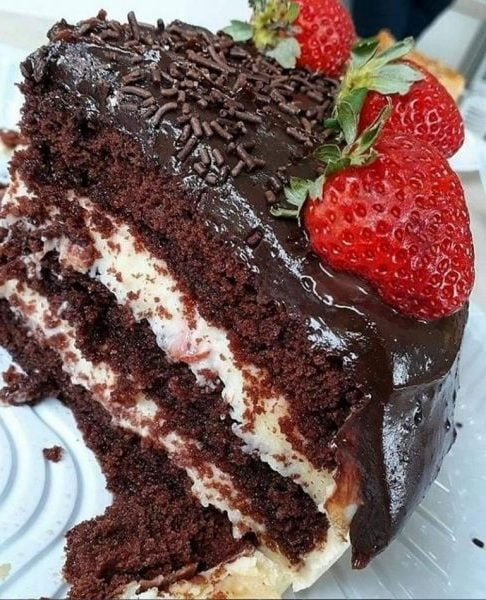 A slice of Chocolate Wet Cake filled with strawberries and topped with condensed milk