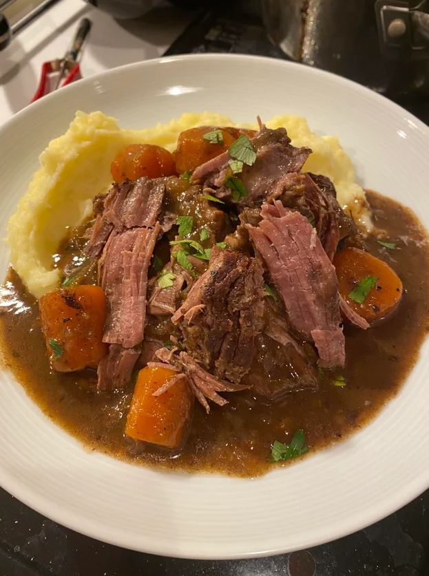 A photo of a tender and juicy pot roast with creamy mashed potatoes.