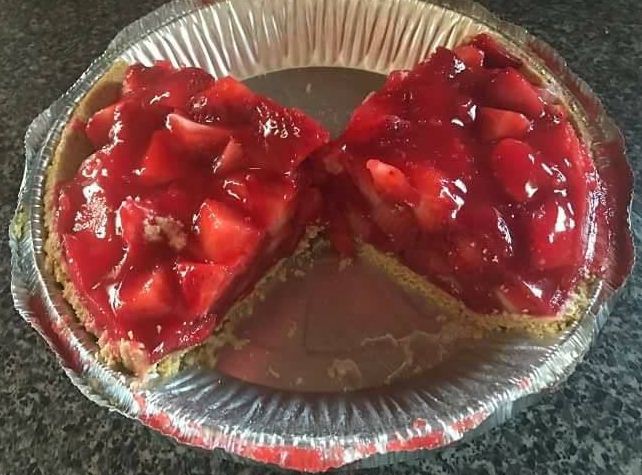 A tempting slice of Big Boys Strawberry Pie adorned with fresh strawberries and a golden crust