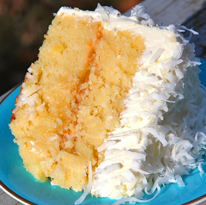 A slice of Old Fashion Coconut Pineapple Cake with fluffy white frosting