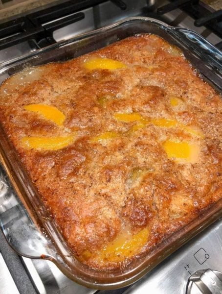 A delicious homemade peach cobbler with a golden brown crust, topped with fresh peaches