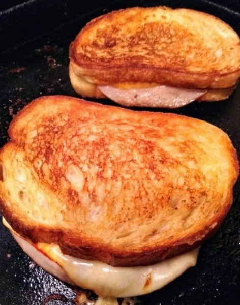 A close-up photo of a golden brown grilled turkey and cheese sandwich cut in half, revealing melted cheese and slices of turkey breast.