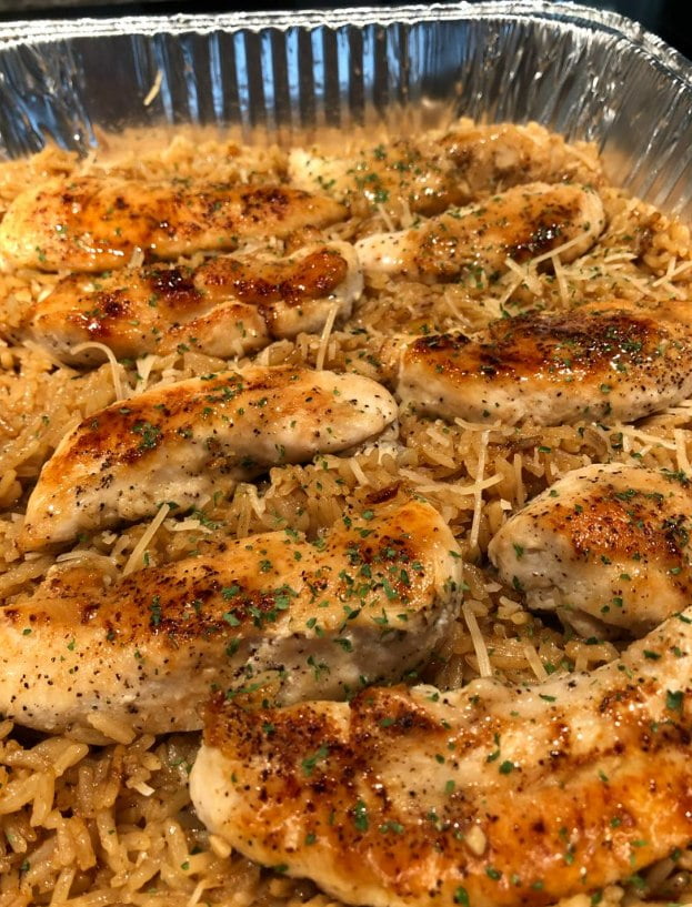 A skillet filled with tender chicken pieces and fluffy rice in a creamy garlic parmesan sauce.