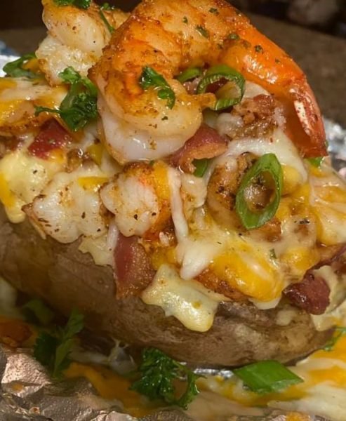 Loaded Seafood Baked Potato with Creamy Cajun Shrimp Sauce - A plate of golden-brown baked potatoes topped with succulent shrimp and a luscious Cajun-infused creamy sauce