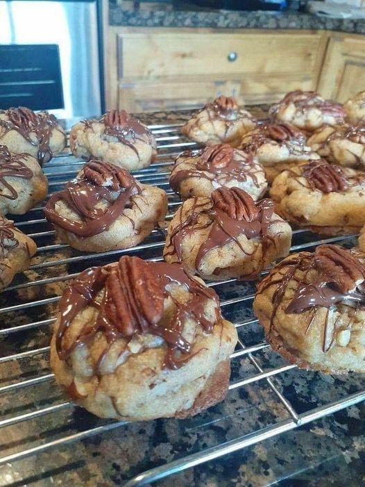 A close-up photo of freshly baked butter pecan cookies on a cooling rack. The cookies are golden brown and studded with chopped pecans.