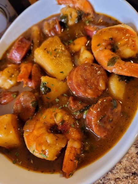 A pot of Shrimp and Sausage Stew with Potatoes cooking on the stove.