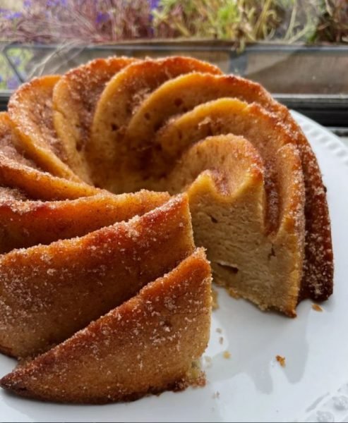Photo of a freshly baked apple cider bundt cake with apples and spices.