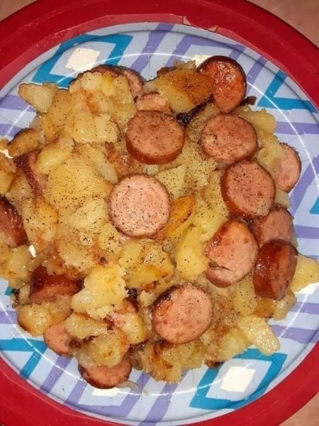 A skillet filled with crispy fried potatoes, onions, peppers, and slices of smoked sausage