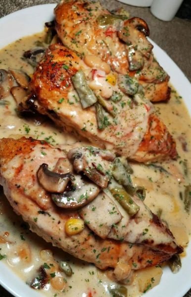 Creamed mushroom chicken breast served on a plate with roasted vegetables