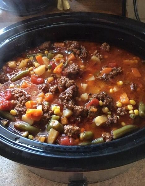 Hearty Crock Pot Cowboy Soup simmering in a rustic pot, showcasing the rich blend of beef, sausage, and farm-fresh vegetables.