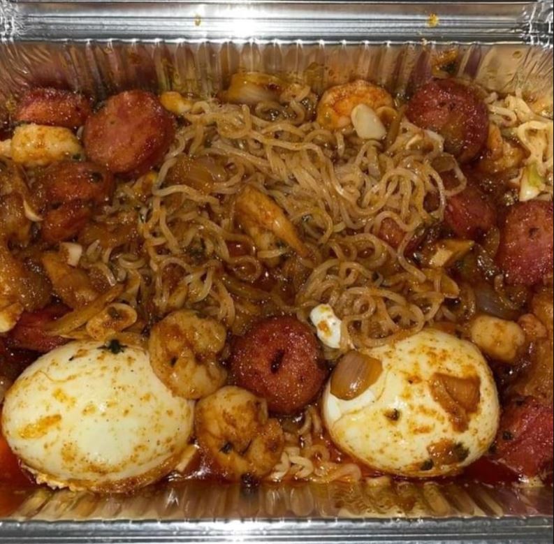 A plate of Ramen Seafood Boil with shrimp, crab, and scallops on top of the ramen noodles