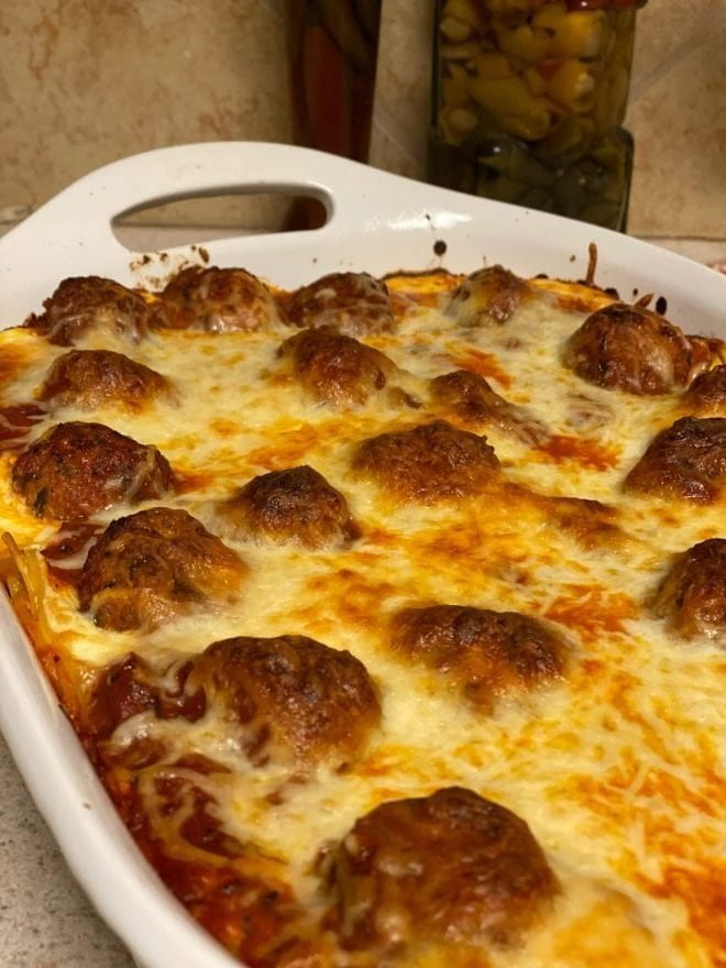 A pan of baked spaghetti and meatballs covered in melted cheese