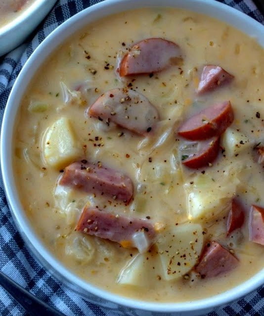 A steaming bowl of Kielbasa Potato Soup, topped with melted cheddar and fresh parsley, ready to delight your taste buds.