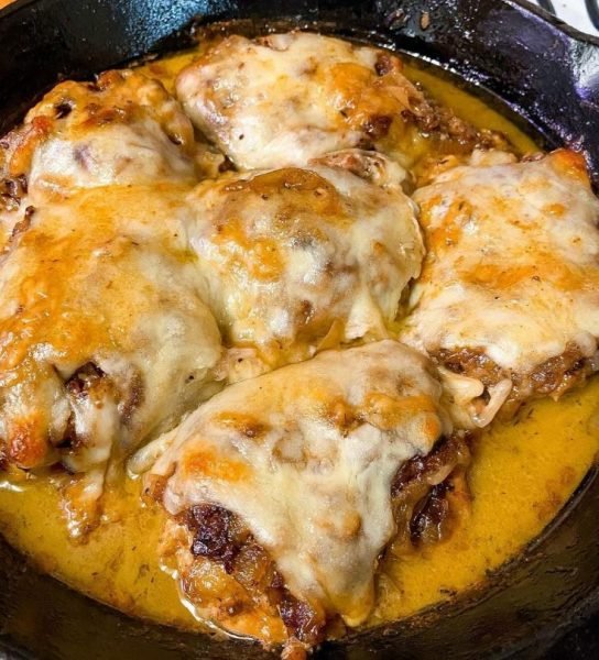 French Onion Chicken Skillet: A golden-brown chicken thigh topped with caramelized onions and melted Gruyère cheese, baked to perfection.