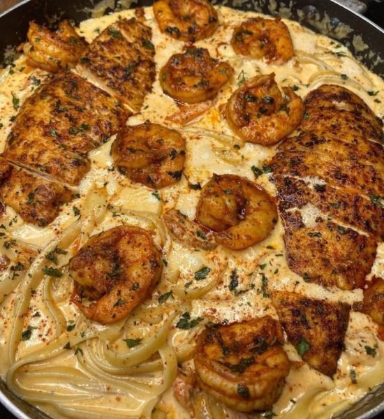 A bowl of Cajun chicken and shrimp Alfredo pasta with a fork on the side