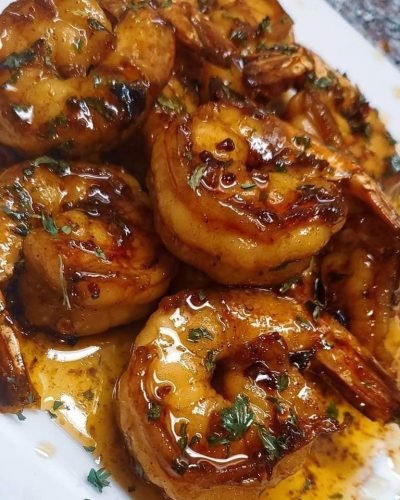 "Henny Butter Shrimp: A plate of succulent shrimp bathed in a rich Hennessy-infused sauce, garnished with fresh parsley."