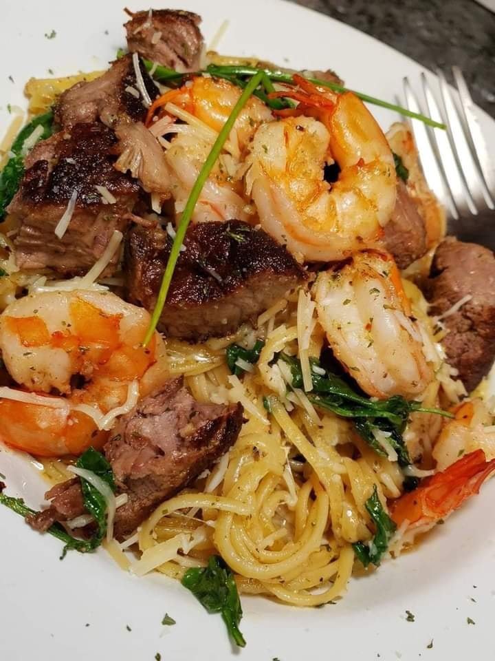 Steak and Shrimp Pasta with Roasted Asparagus on a plate with grated Parmesan cheese on top