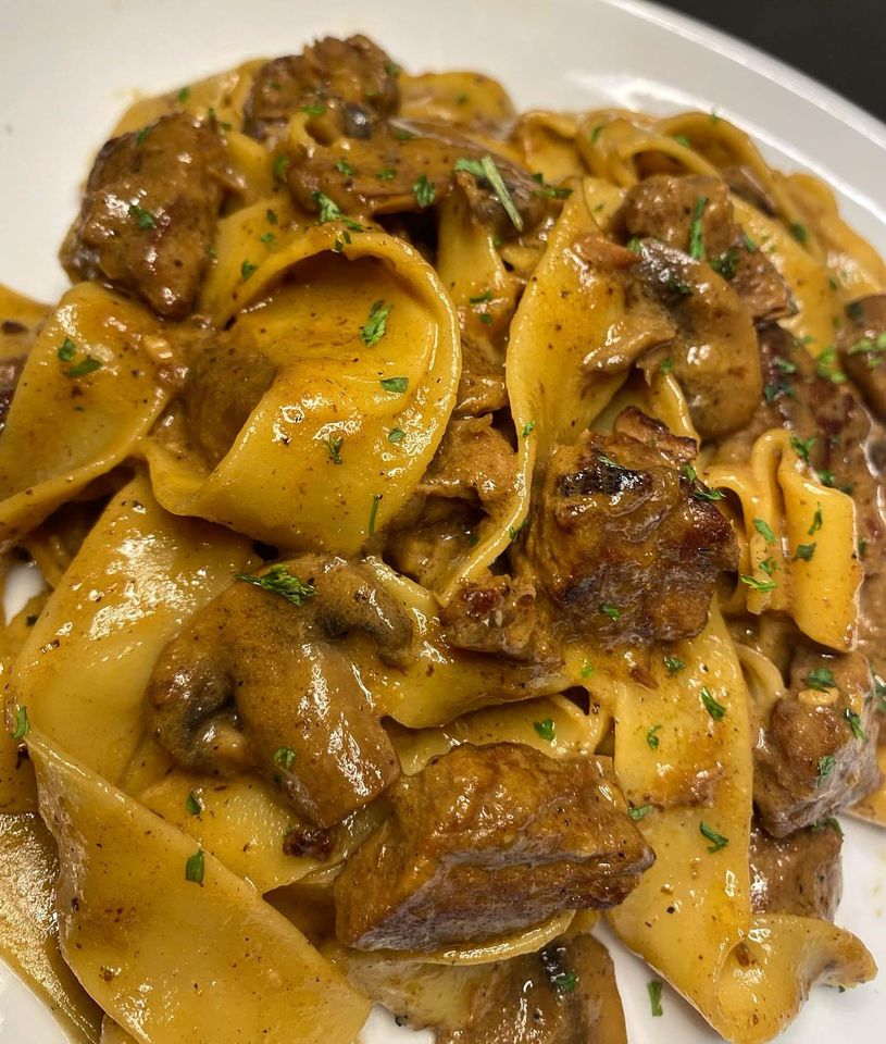 Image of a plate of Beef Stroganoff served over a bed of pasta.