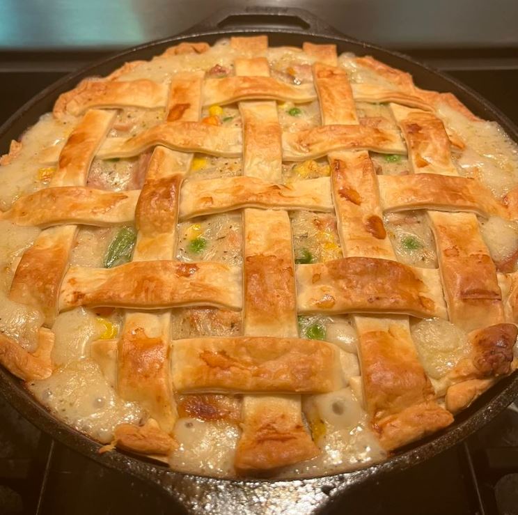 A slice of chicken pot pie in a golden-brown crust, topped with a lattice pattern of pastry strips.