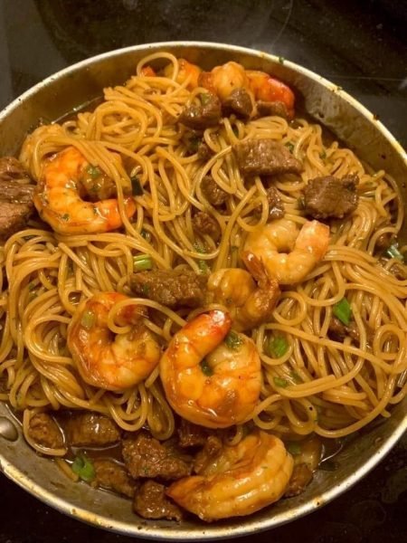 A bowl of shrimp and steak teriyaki noodles, with thin noodles, sliced steak, and shrimp covered in a glossy teriyaki sauce.