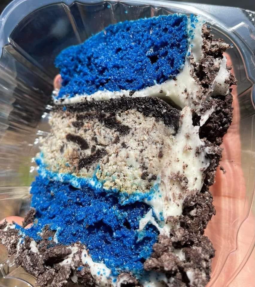 A slice of Blue Velvet Oreo Cheesecake Cake on a white plate