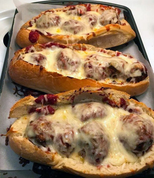 "Meatball Boats - Juicy ground beef meatballs on a bed of melted Asiago cheese in a perfectly hollowed hoagie roll, a gastronomic delight.