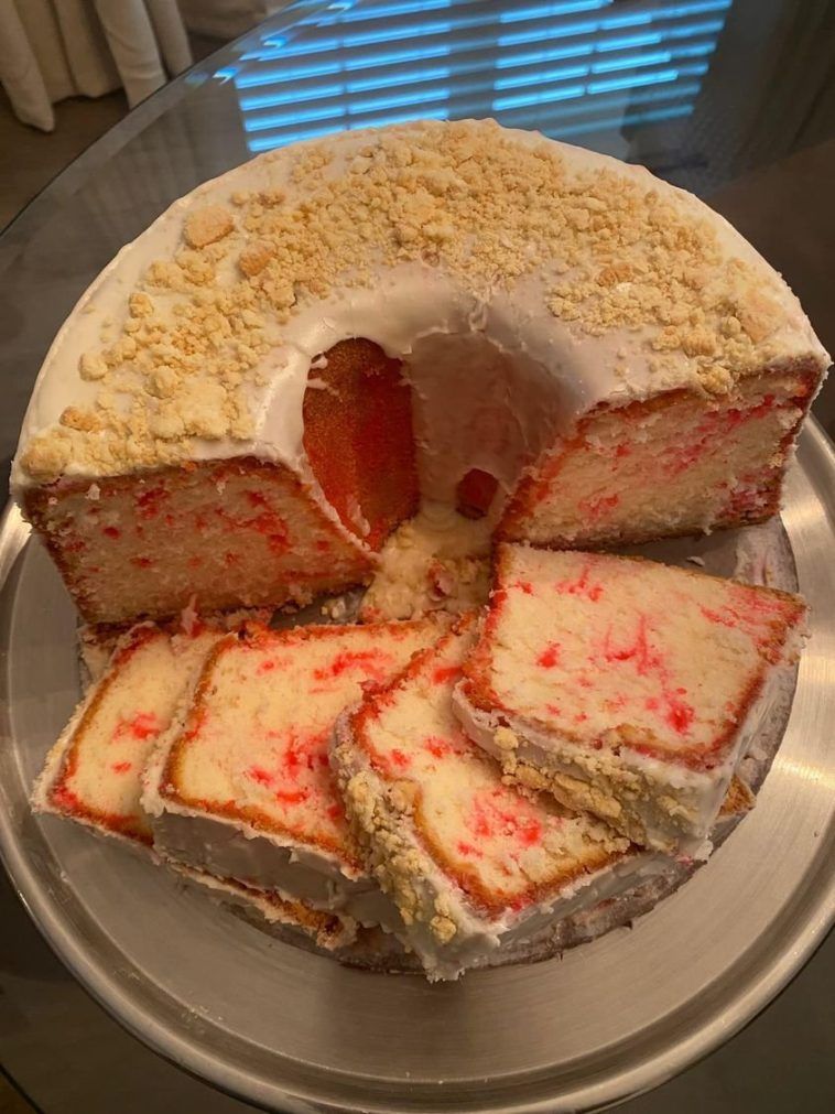 A slice of strawberry crunch pound cake with fresh strawberries and crushed graham crackers on top