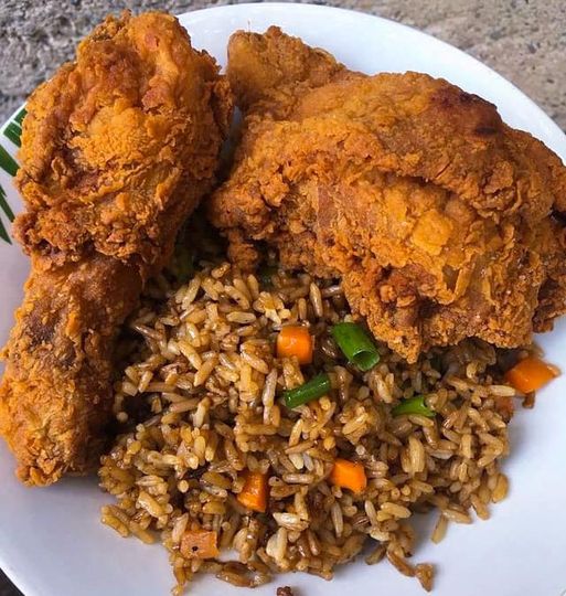 Crispy fried chicken served with brown rice on a white plate.