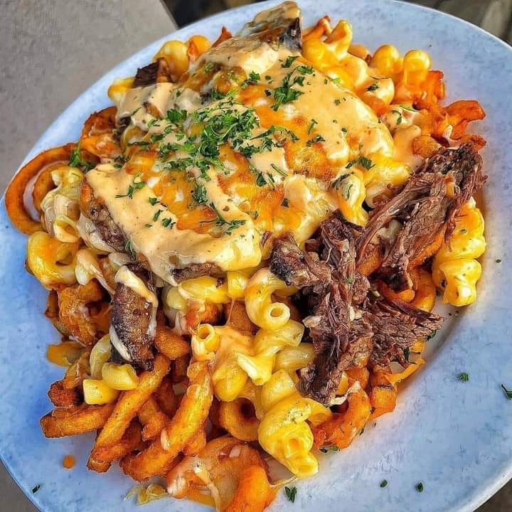 A plate of short rib mac & cheese fries, with tender short ribs, creamy macaroni and cheese, and crispy French fries
