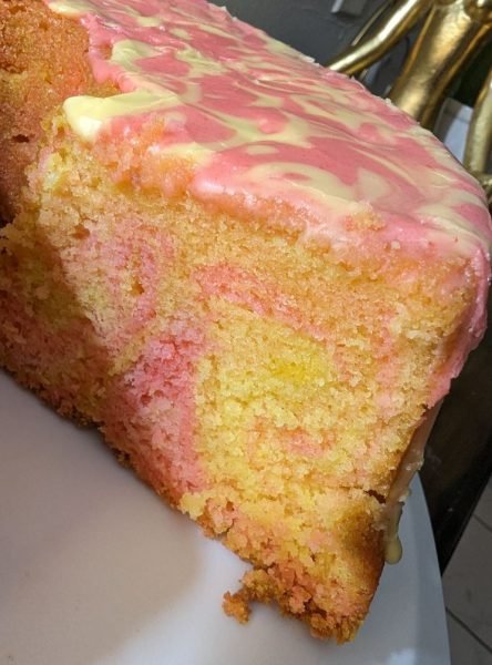 A slice of strawberry lemon swirl pound cake on a plate with a strawberry lemonade drizzle.