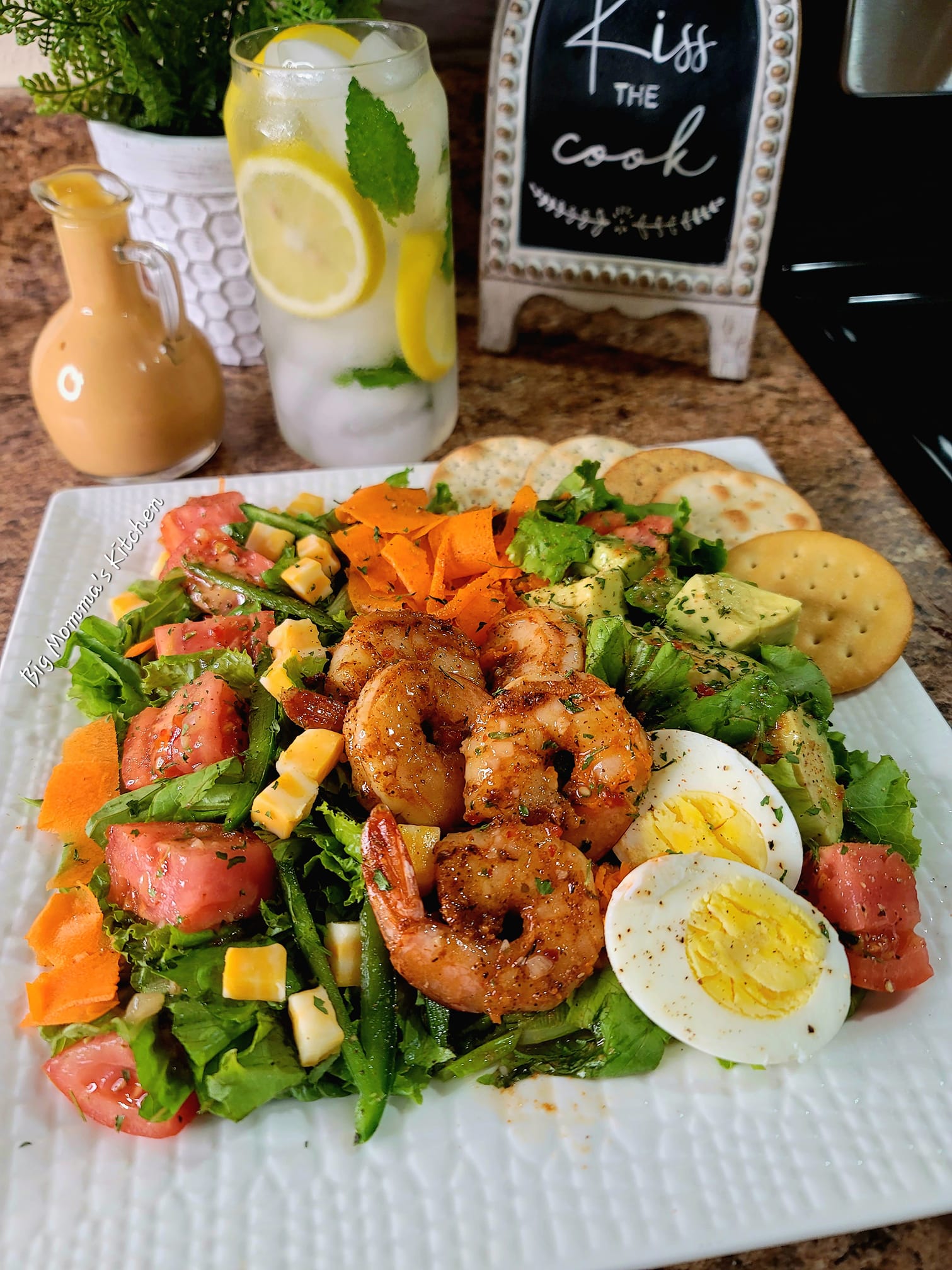 A bowl of grilled shrimp and avocado salad with tomato, hard boiled egg, and shredded carrot