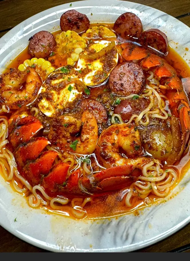 Seafood boil ramen with shrimp, crab, sausage, boiled eggs, and ramen noodles in a rich seasoned broth.