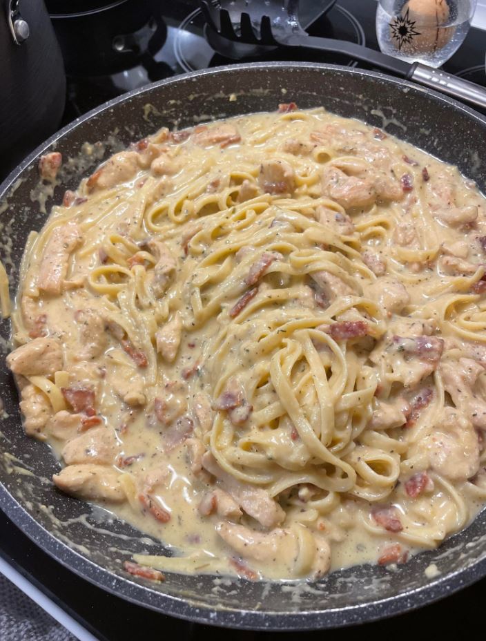 Image of a plate of creamy Chicken Carbonara pasta, with a fork digging into the noodles and sauce.
