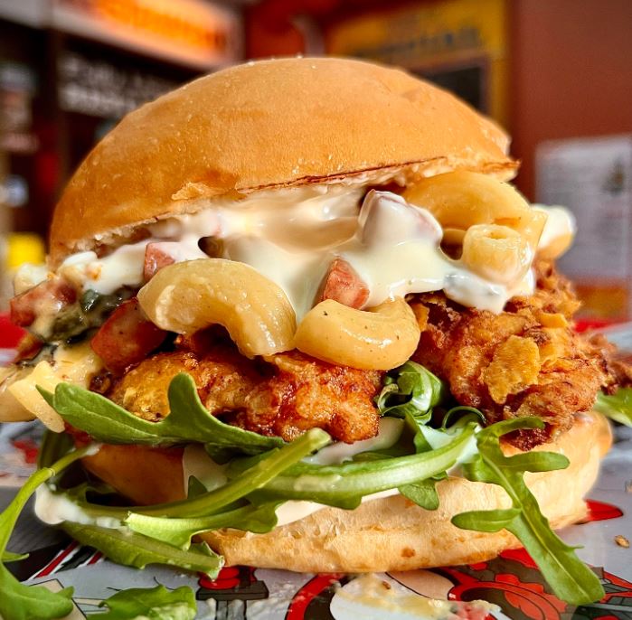 A delicious and juicy fried chicken breast coated in crushed Doritos and served with Nacho Flavored Mac, Diced Chorizo, Grilled Jalapeños, Sour Cream Aioli, and Fresh Arugula.