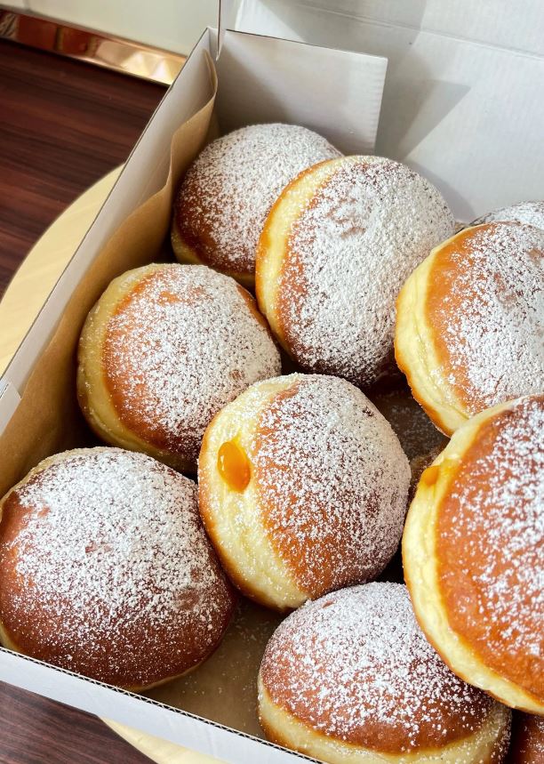 A plate of freshly baked homemade jam donuts, also known as krafne or paczki.