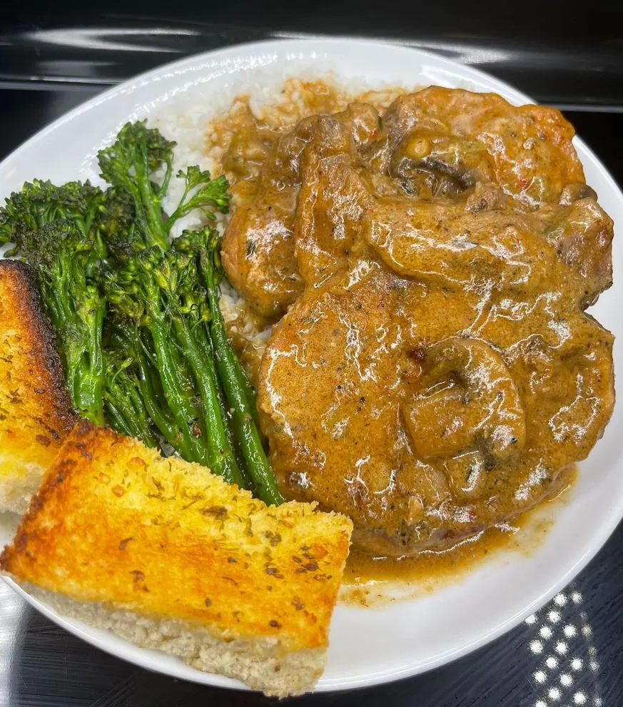 Cream of mushroom pork chops with rice, broccolini, and garlic bread