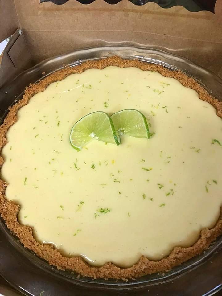 Close-up slice of key lime pie with whipped cream and lime wedge.