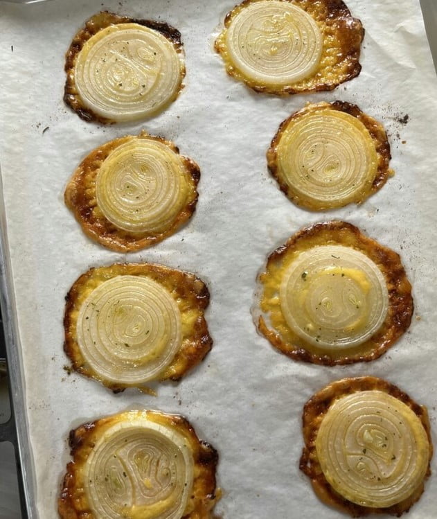 Cheesy Onion Crisps on a white plate – a crispy, golden delight topped with cheddar cheese and ranch seasoning.