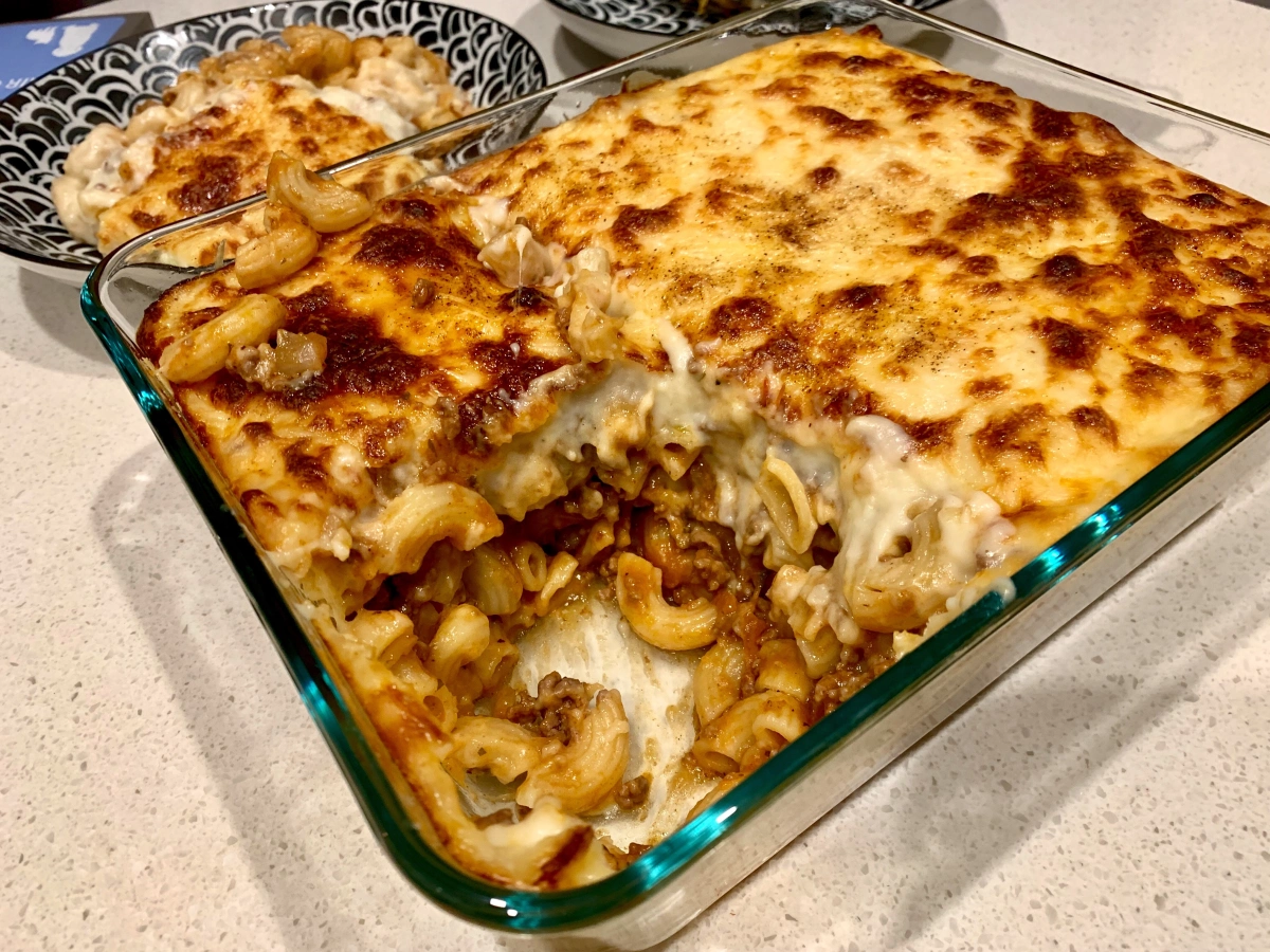 A close-up image of a baked pasta dish with bubbling melted cheese, ground beef, and tomato sauce.